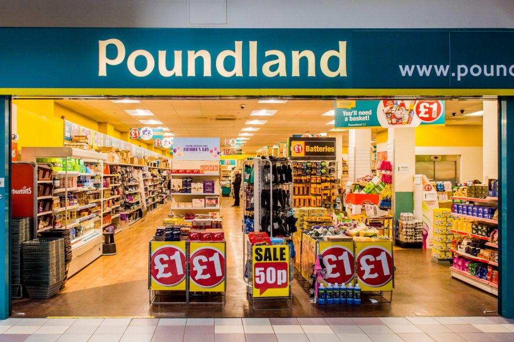 Entrada de una tienda Poundland en Reino Unido con carteles de ofertas de £1, representando el modelo de negocio de bajo coste en plena reestructuración concursal.